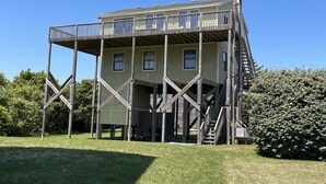 Une structure en bois à plusieurs étages, dotée d’un balcon au niveau supérieur et entourée de verdure.