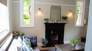 A living room with a fireplace, a sofa, a table, and two windows. - Lock Keepers Cottage - Detached House in the City (Manchester)