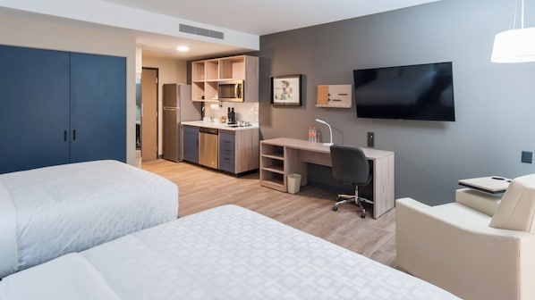 Une chambre d’hôtel avec deux lits, une kitchenette, un bureau, une chaise et un téléviseur.