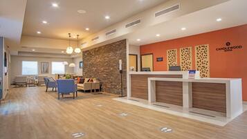 A modern reception area with a stone wall, a reception desk, and a seating area with chairs and a sofa.