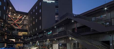 Un hotel de varios pisos con un letrero llamativo de 'Candlewood Suites', una clínica 'Dental Sense' y un restaurante 'Kachettis'.