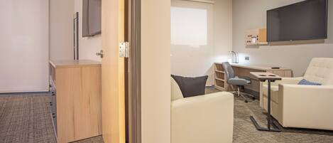 Une chambre d’hôtel moderne équipée d’un bureau, d’une chaise et d’un téléviseur fixé au mur.