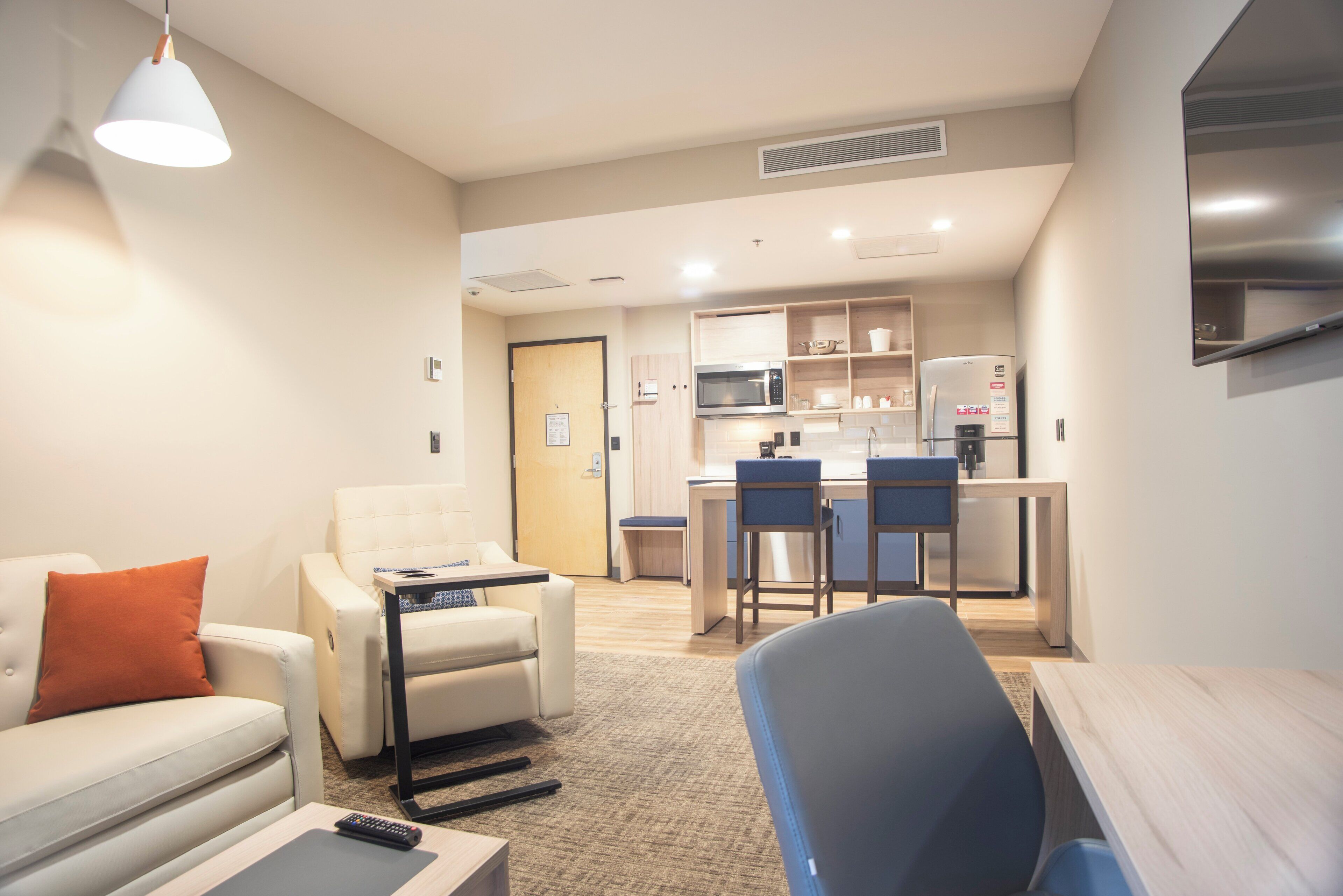 A compact living space with a kitchenette, a sofa, a coffee table, and a TV.