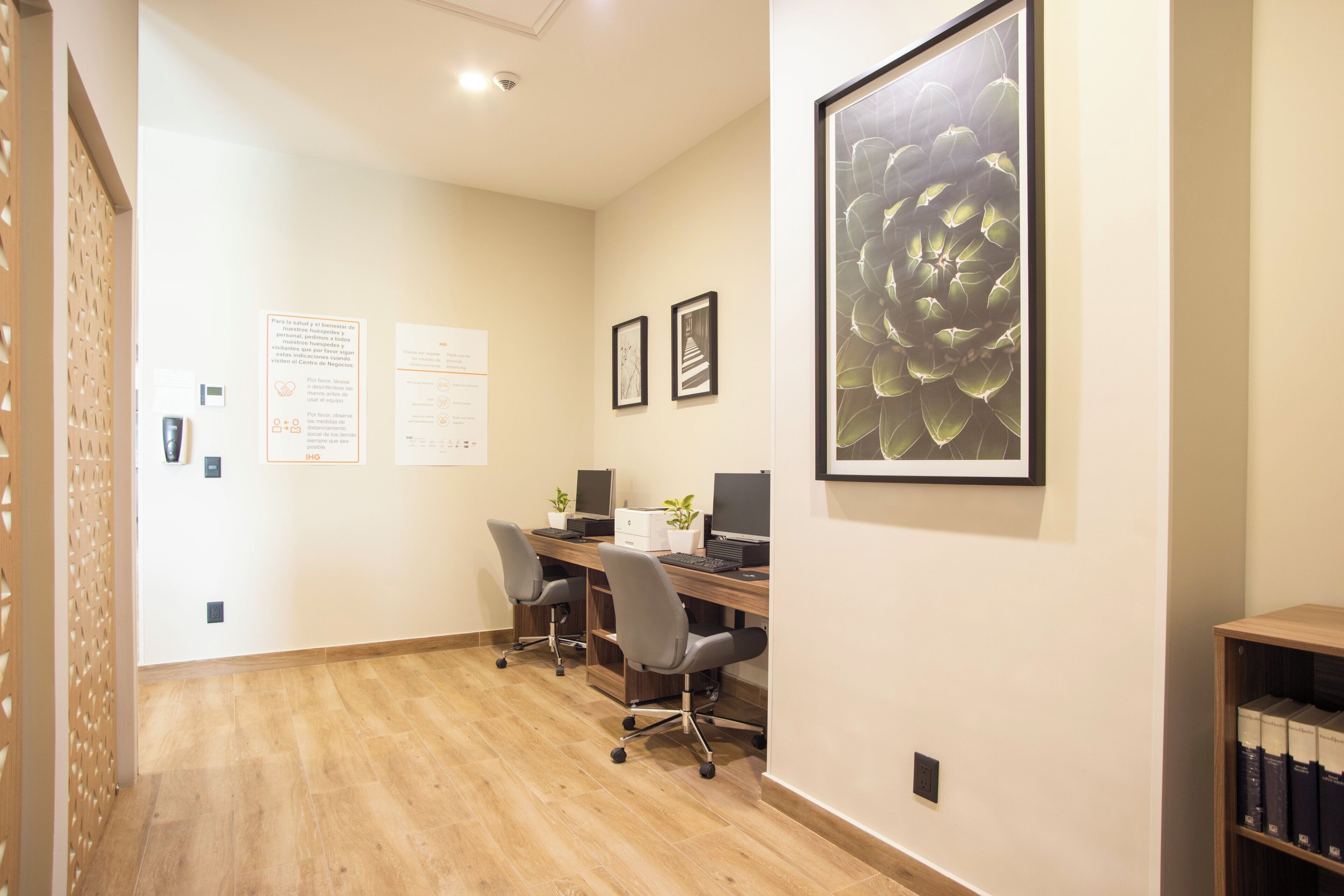 A modern office space with a wooden floor, a desk with two chairs, and a large framed artwork on the wall.