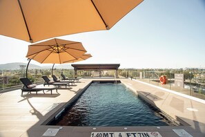 A rooftop pool with lounge chairs and umbrellas, a lifebuoy, and a sign indicating no diving. - Candlewood Suites Guadalajara Galerias by IHG (Zapopan)