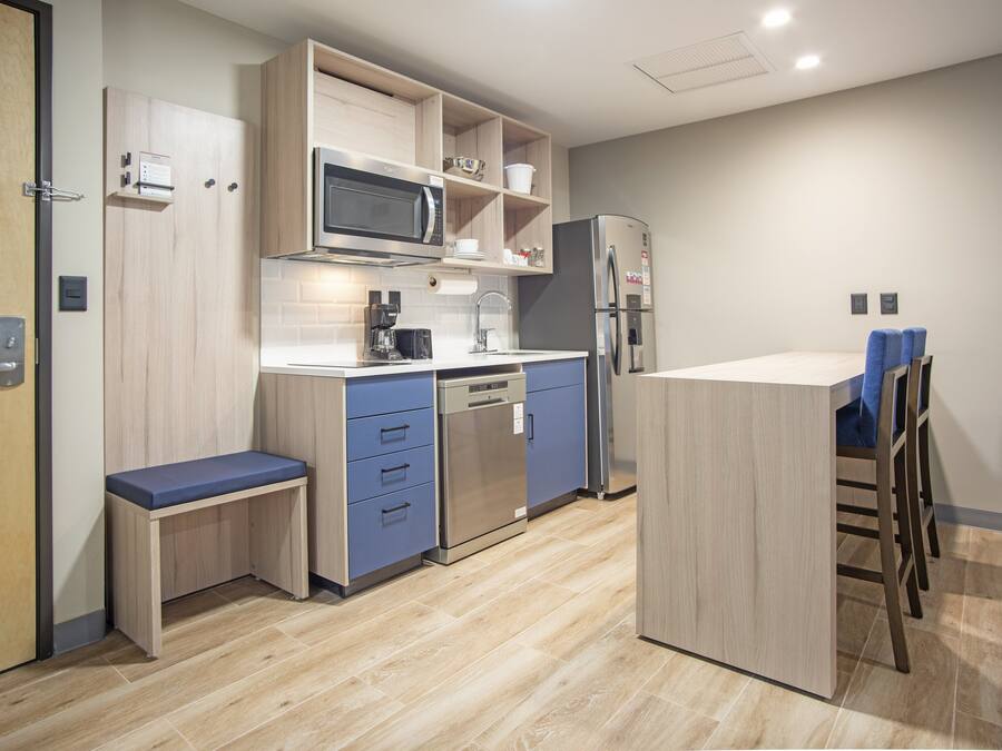 A modern kitchen with wooden cabinets, a built-in microwave, a dishwasher, and a refrigerator.
