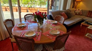 Un comedor con una mesa redonda dispuesta para cuatro personas, rodeada de sillas de mimbre.