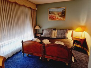 A hotel room with a wooden bed, a painting on the wall, a lamp, and a window with curtains. - Paradise lake view Apartment (Veytaux)