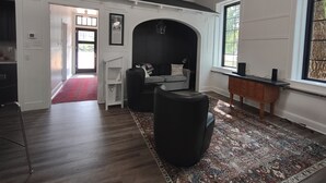 A modern living room with a dark sofa, a patterned rug, and a wooden sideboard. - Restored school house turned creative flex space (Perham)