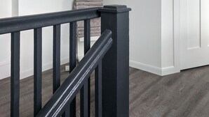 A staircase with a black railing leading to a landing. A white door is visible to the right. - Restored school house turned creative flex space (Perham)