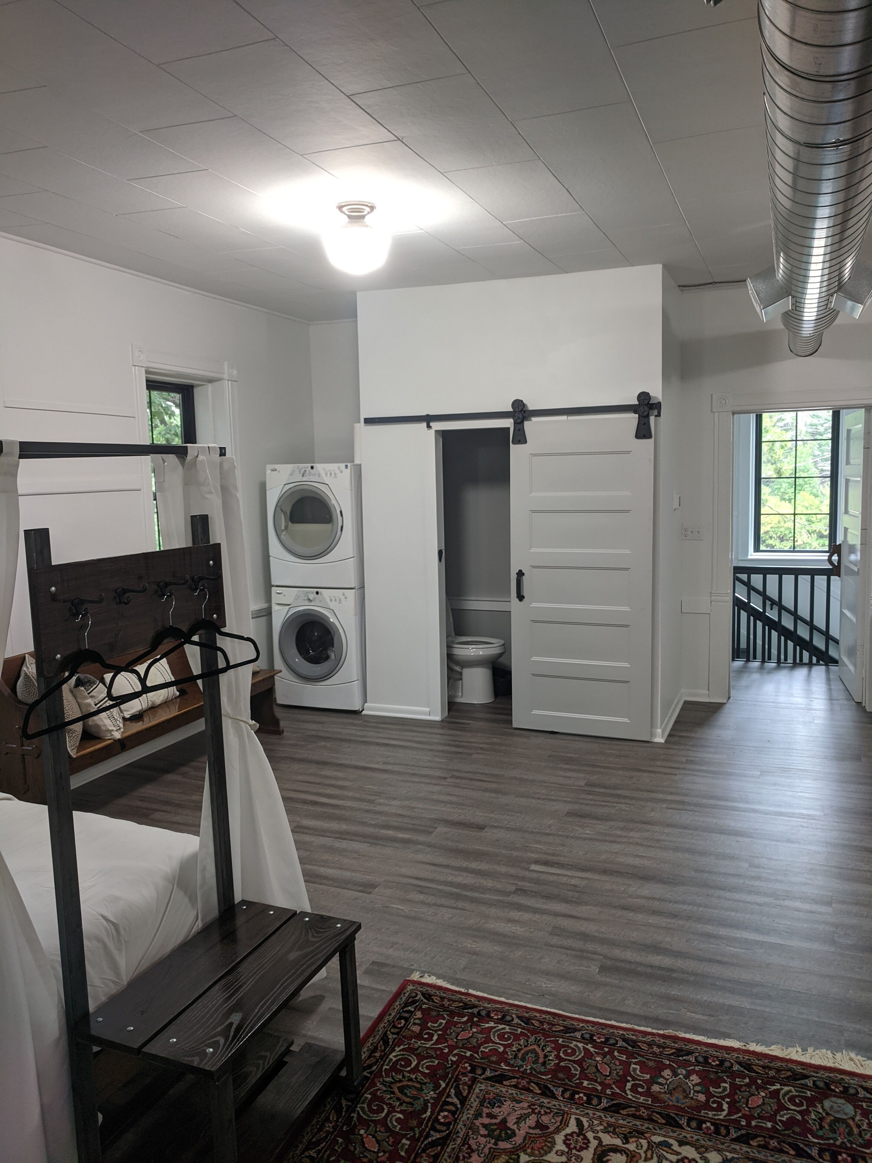 Une chambre d’hôtel équipée d’un lit, d’une machine à laver, de toilettes et d’une porte coulissante donnant sur un balcon.