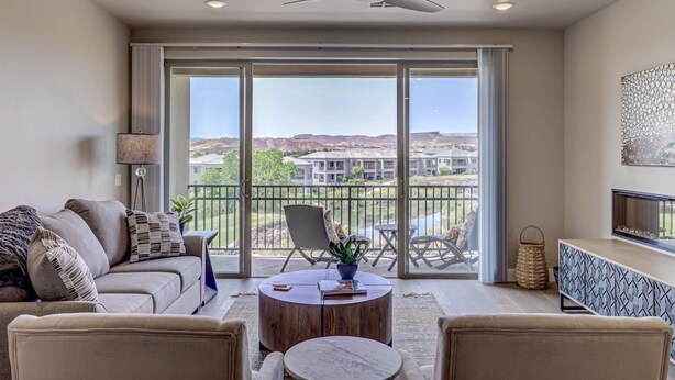 A spacious living room with a large sliding glass door leading to a balcony, a ceiling fan, and a modern fireplace. - Golfers Getaway in Secluded and Quiet Setting, Golf Course and Mountain Views! (St. George)