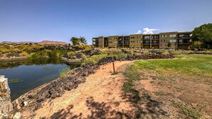 A multi-story building with a pool, surrounded by a landscaped area with a dirt path and sparse vegetation. - Golfers Getaway in Secluded and Quiet Setting, Golf Course and Mountain Views! (St. George)