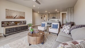A modern living room with a sofa, armchairs, a coffee table, and a dining area with a kitchen in the background. - Golfers Getaway in Secluded and Quiet Setting, Golf Course and Mountain Views! (St. George)