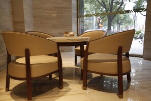 A modern interior with a round table and four chairs with woven seats. - Ji Hotel (Shanghai)