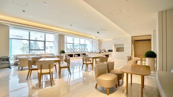 A modern hotel lobby with a central seating area, a reception desk, and large windows providing natural light. - Ji Hotel (Shanghai)