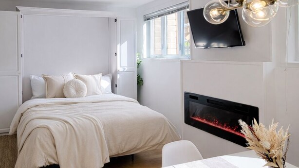 A modern bedroom with a bed, a TV mounted on the wall, and a fireplace. - WESKI | Grand studio - Seasonal prices 🌿 (Beaupré)