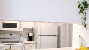 A modern kitchen with white appliances, a sink, and three wooden stools. - WESKI | Grand studio - Seasonal prices 🌿 (Beaupré)