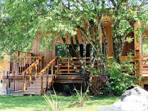 Une cabane en bois dotée d’une terrasse en bois, d’un escalier et d’un espace salon abrité.