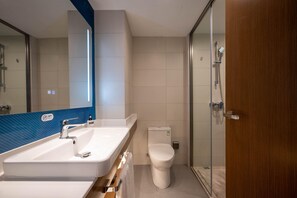 Une salle de bain moderne équipée d’un lavabo, de toilettes et d’une zone douche.
