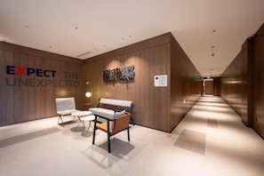 A modern lobby with a bench, chairs, and a wall with the text 'EXPECT THE UNEXPECTED.'