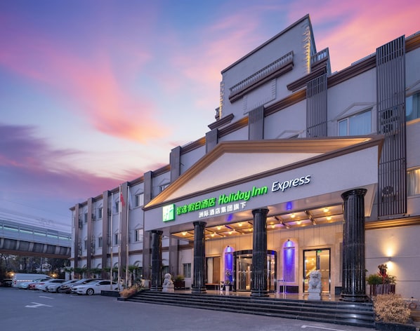 Entrada de un hotel con fachada moderna, amplias columnas y el letrero de Holiday Inn Express.