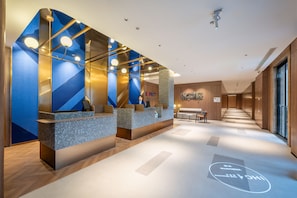 Uma área de recepção moderna com esquema de cores azul e dourado, um balcão e uma placa com a inscrição 'EXPECT LUXURY'.