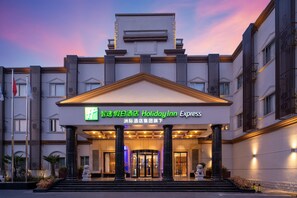 Entrada de um hotel Holiday Inn Express, com uma placa de destaque, colunas imponentes e uma entrada majestosa.
