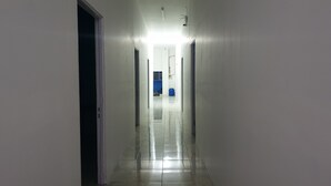 A narrow, well-lit hallway with a tiled floor, leading to a room with a blue wall and a visible door. - OYO 3508 Griya Aisyah Karah Syariah (Surabaya)
