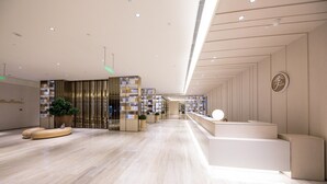 A modern hotel lobby with a reception desk, seating area, and a plant. - Ji Hotel Beijing West Railway Station South Square (Beijing)