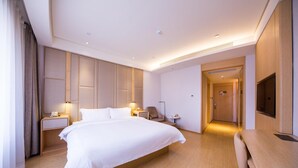 A hotel room with a large bed, bedside tables, a desk, a chair, a TV, and a door leading to another room. - Ji Hotel Beijing West Railway Station South Square (Beijing)
