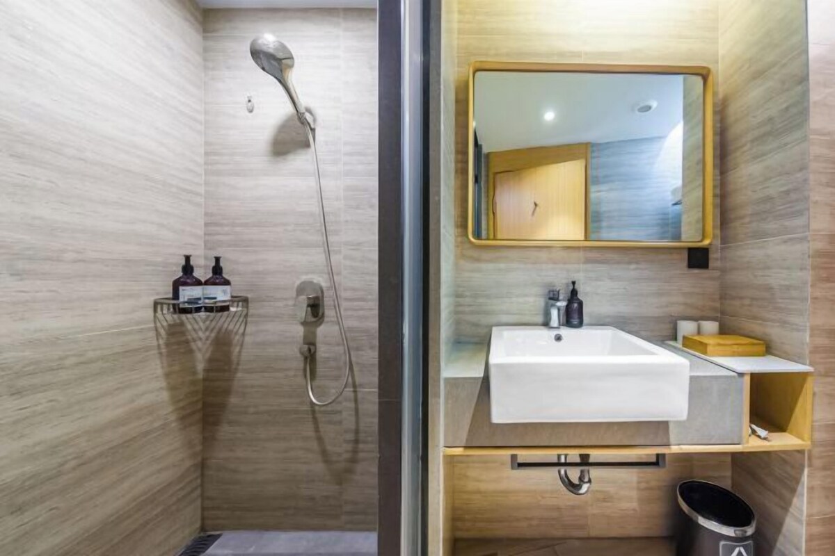 A modern bathroom with a shower, a sink, and a mirror.