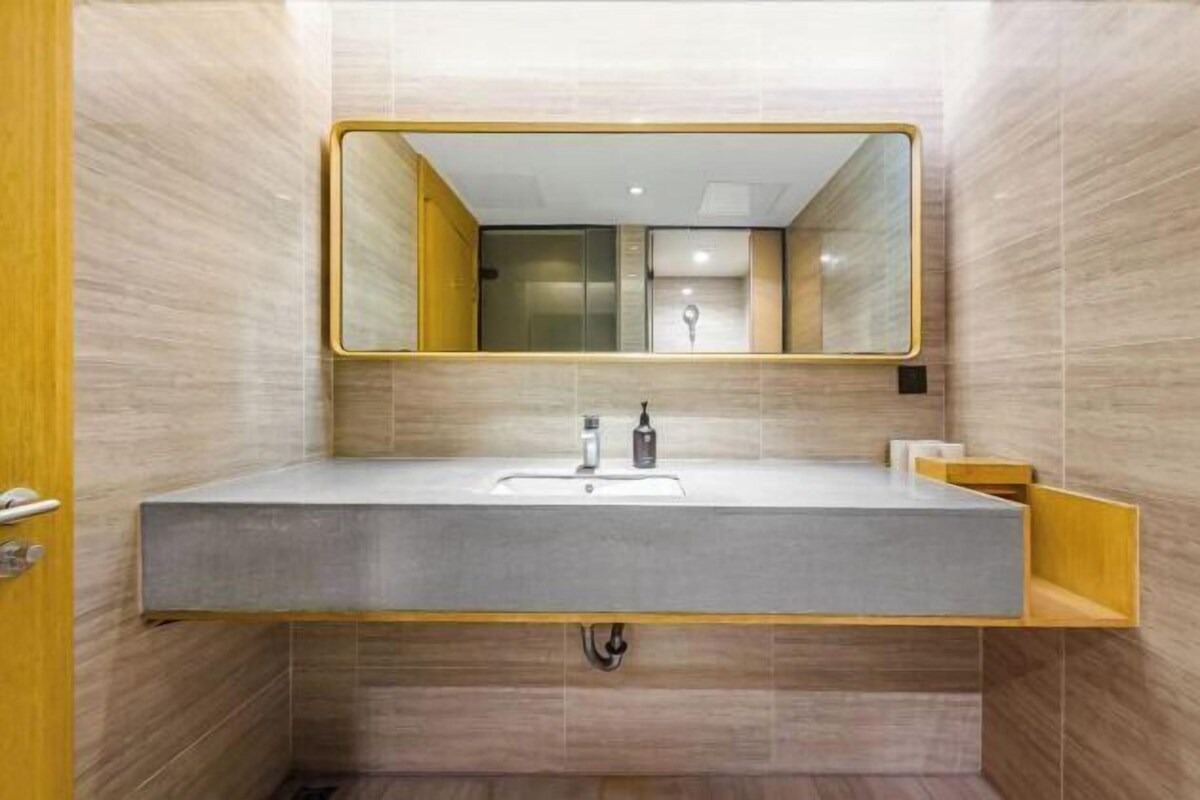 A modern bathroom with a large mirror, a sink, and a wooden vanity.