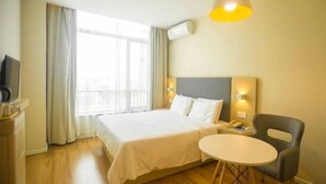 Een hotelkamer met een bed, nachtkastje, stoel en een klein rond tafeltje.
