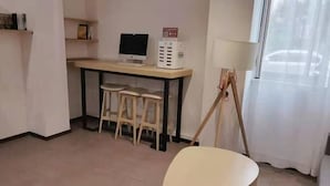 Een kamer met een bureau, computer en twee krukken.