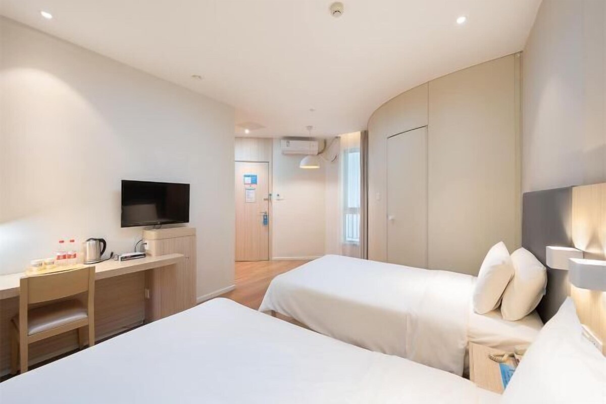 Een hotelkamer met twee bedden, een televisie, een bureau en een kledingkast.
