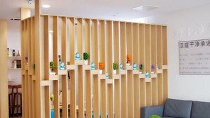Een modern interieur met een houten scheidingswand, een grijze bank en een ronde tafel met een plant.