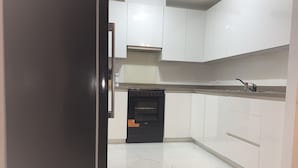 A kitchen with white cabinets, a black oven, and a stainless steel countertop. - Stratford city apartment (London)