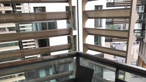 A balcony with wicker furniture and a glass table. - Stratford city apartment (London)