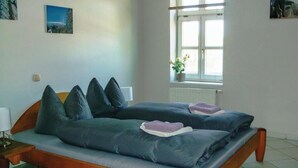 A bedroom with a bed, pillows, a bedside table, a lamp, a window, and a potted plant. - Amazing Apartment in Wernigerode With Wifi and 2 Bedrooms (Wernigerode)
