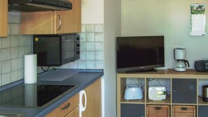 A kitchen with a microwave, a flat-screen TV, a coffee maker, and a toaster on a wooden shelf. - Amazing Apartment in Wernigerode With Wifi and 2 Bedrooms (Wernigerode)