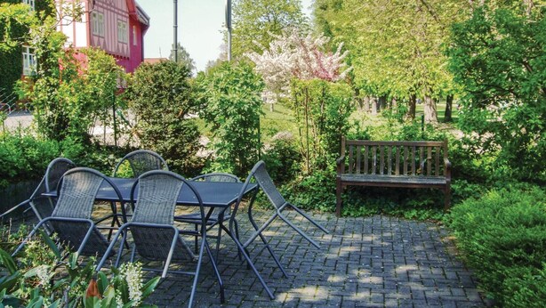 A patio with a table and chairs, surrounded by greenery and a bench. - Amazing Apartment in Wernigerode With Wifi and 2 Bedrooms (Wernigerode)