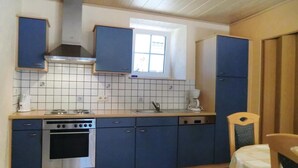 A compact kitchen with blue cabinets, a stove, and a window above the sink. - Awesome Home in Hachiville With Wifi and 1 Bedrooms (Wincrange)