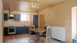 A compact kitchen with a stove, oven, and a window above the sink. There is a dining table with chairs and a radiator on the floor. - Awesome Home in Hachiville With Wifi and 1 Bedrooms (Wincrange)