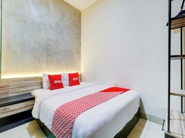 Una habitación de hotel con una cama, cabecera y estante en la pared.