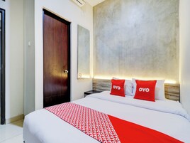 Habitación de hotel con cama, una puerta de madera y un espejo grande sujeto a la pared.