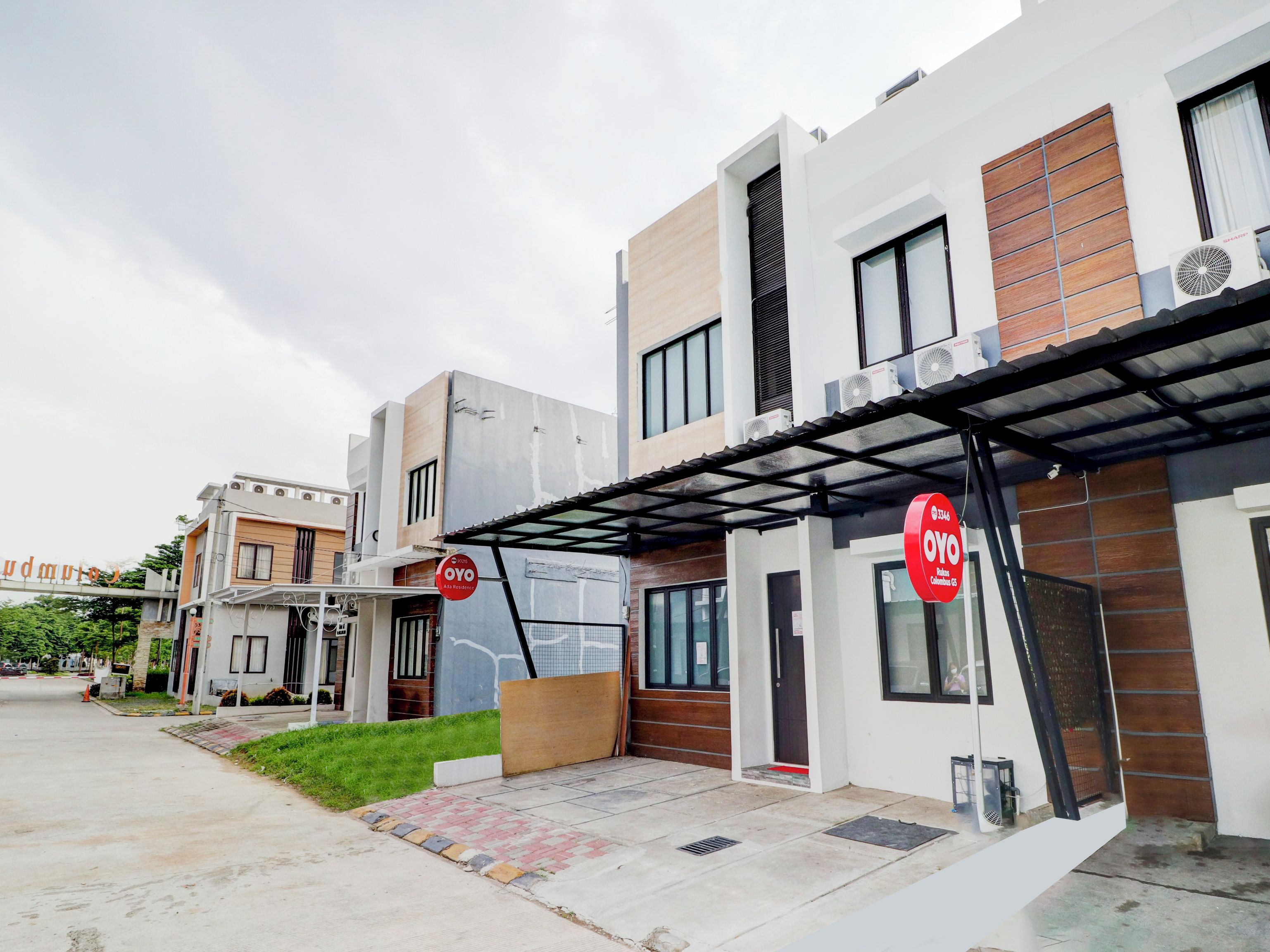 A modern residential building with a covered entrance, a visible door, and a sign indicating a residential area.