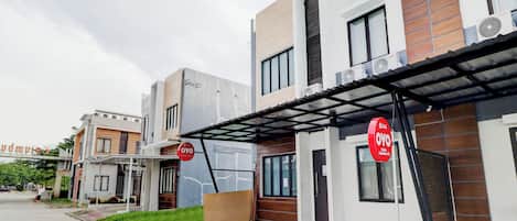 A modern residential building with a covered entrance, a visible door, and a sign indicating a residential area.