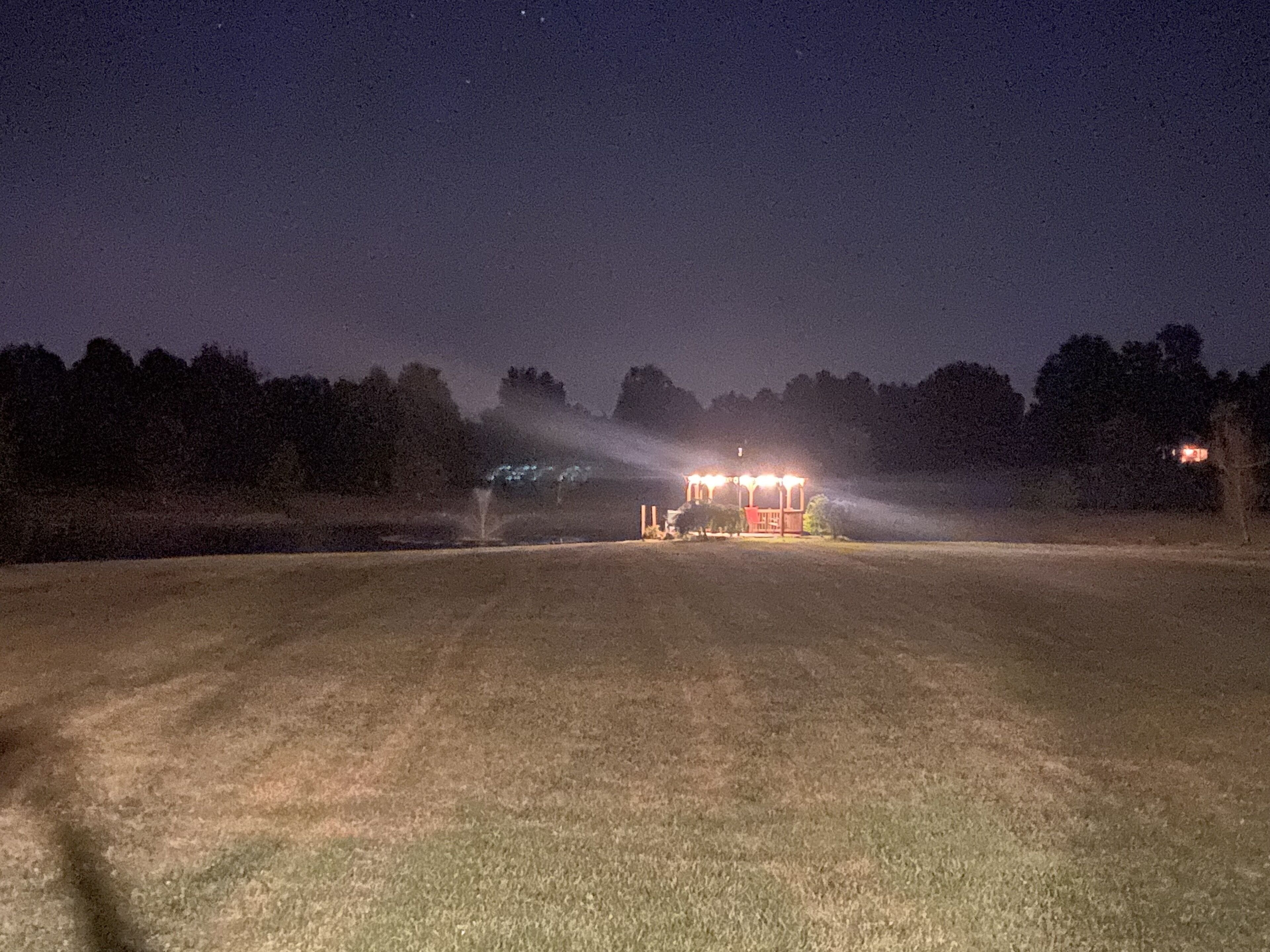 Vista nocturna de un campo con un edificio iluminado por luces.