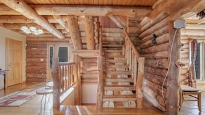 A log cabin interior with a wooden staircase, a wooden railing, and a fireplace. - special offers: 20% off all winter bookings,10% discount for early reservations. (Baltimore)
